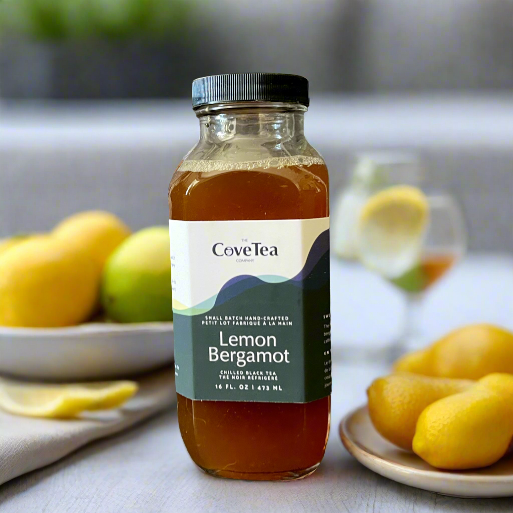 Cove Tea’s Lemon Bergamot Chilled Tea set on a table with fresh lemons and bergamot, with two glasses of ice waiting in the background.