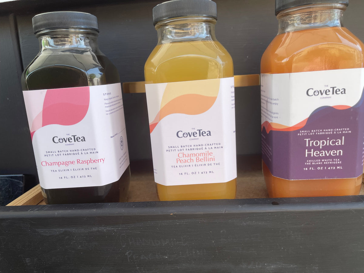 Three bottles of iced teas and elixirs sitting on a small black shelf. 