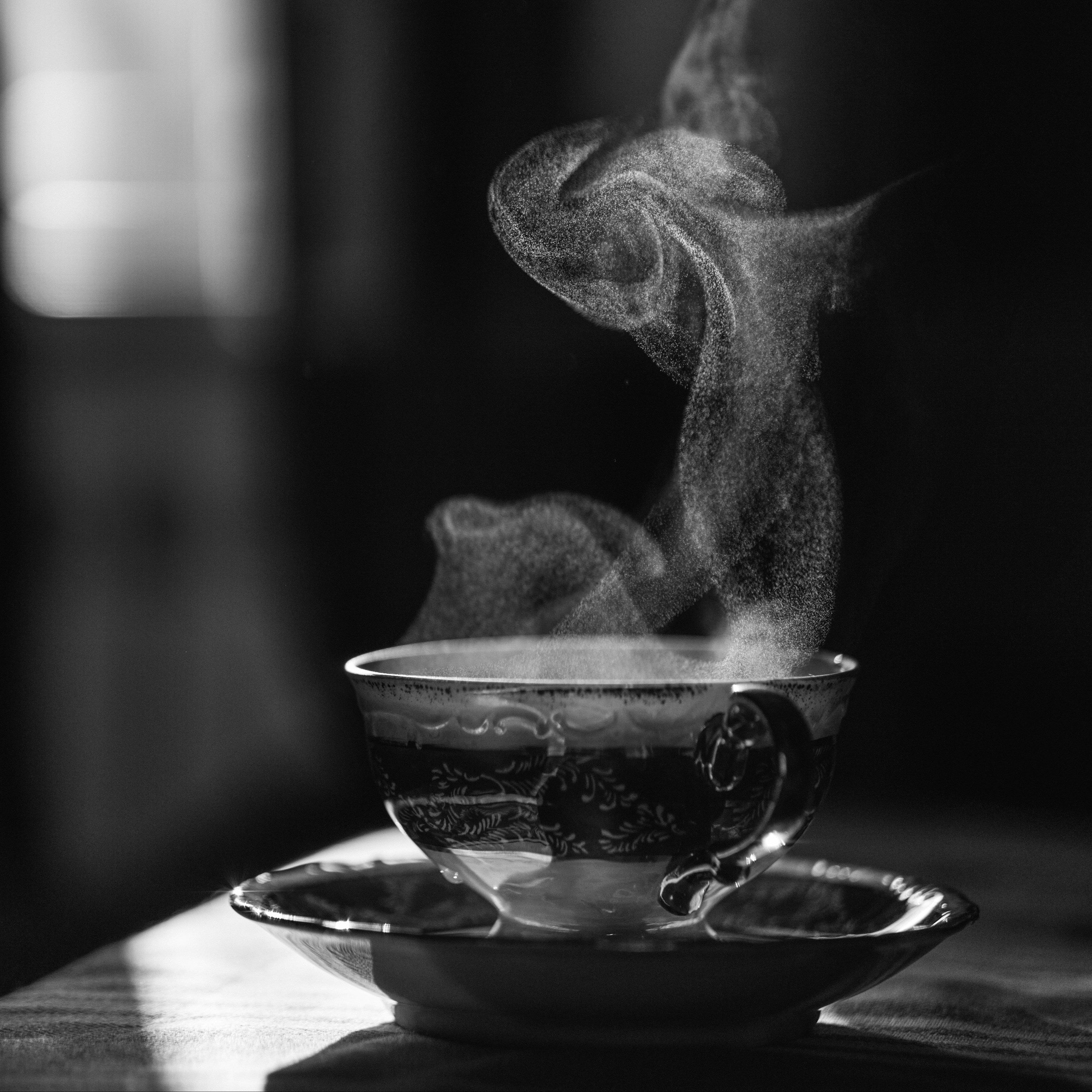 Steaming cup of tea on a saucer with a blurred background