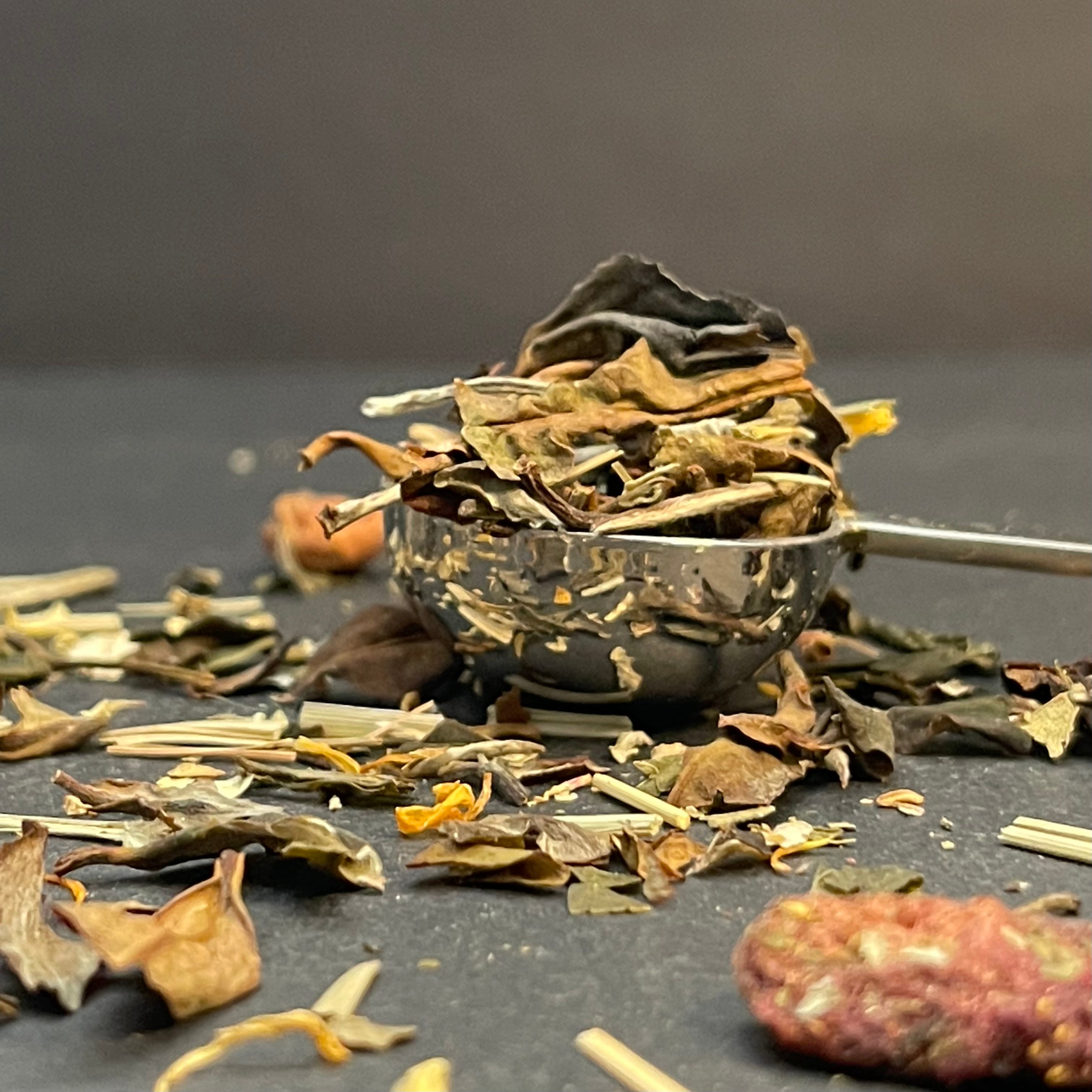 Midsummer’s Dream Tea leaves in a metal scoop on a dark surface