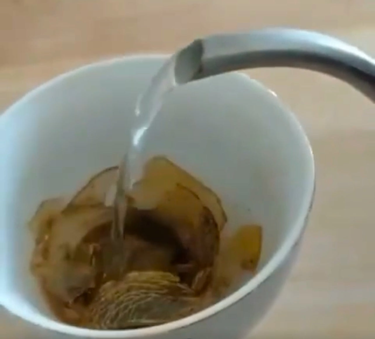 The Cove Tea Company artisan tea bomb mid-explosion in a vintage teacup