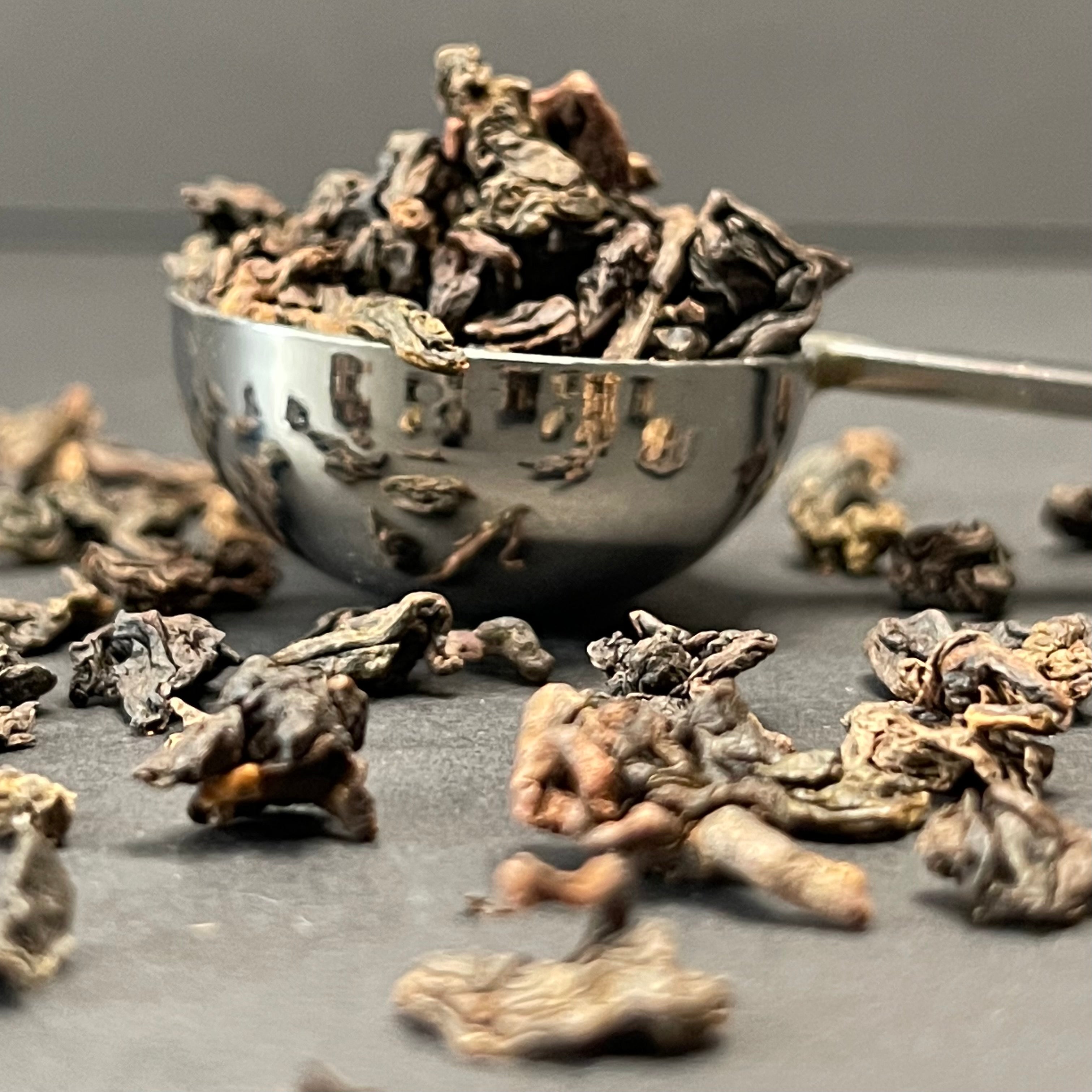 Purple Oolong: Hand-rolled dark purple oolong tea leaves on a white ceramic surface.